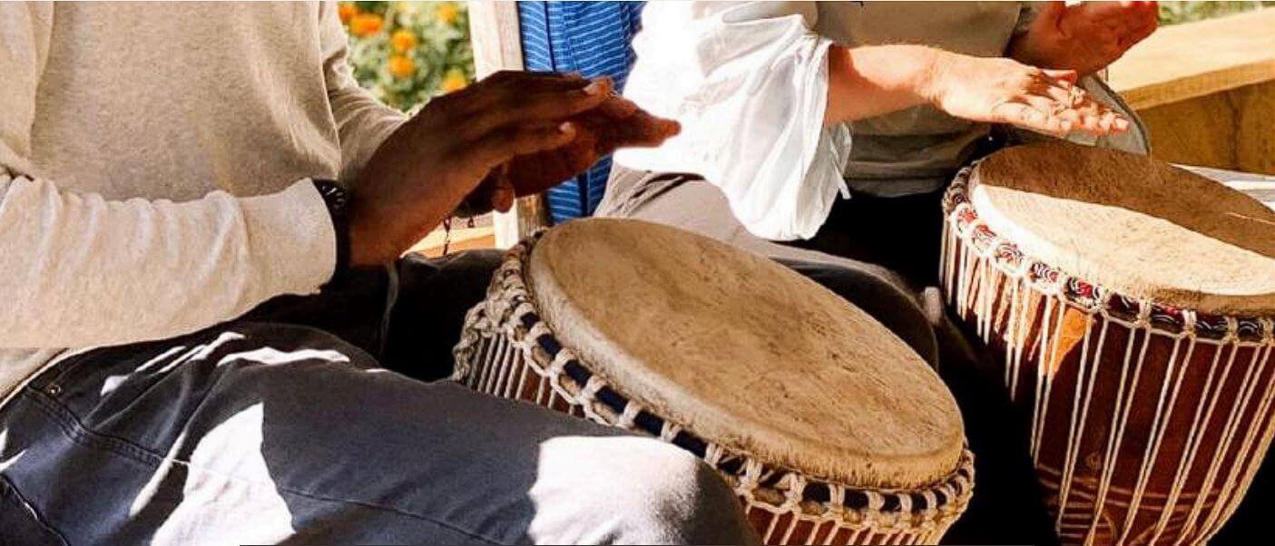 Teilnehmer eines Events auf der Sandai Farm spielen traditionelle Trommeln in entspannter Atmosphäre bei sonnigem Wetter.